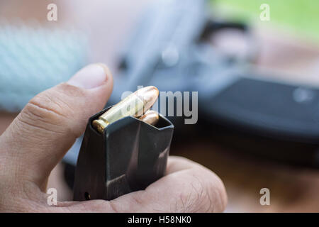 Last 9mm Munition in der Pistole Clip hautnah. Hände, Kugeln, Magazin und Pistole. Stockfoto
