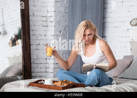 Blonde Dame frühstücken und Buch Stockfoto
