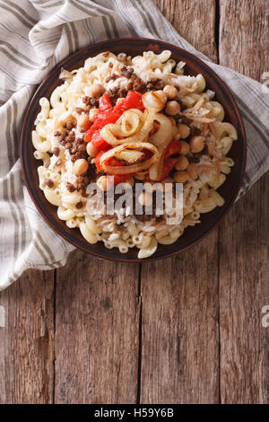 Arabische Küche: Kushari von Reis, Nudeln, Kichererbsen und Linsen auf einem Teller vertikale Ansicht von oben Stockfoto