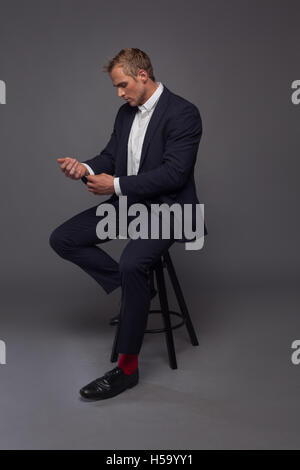 elegante junge Mode Mann im Smoking auf dem Stuhl sitzend Stockfoto