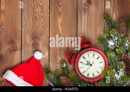 Weihnachten aus Holz Hintergrund mit Uhr, Nikolausmütze, Schnee Tanne Baum und Kopie Raum Stockfoto