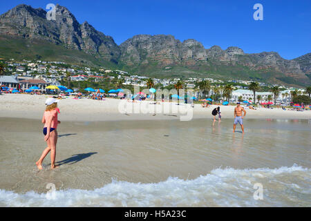 Menschen, die an einem heißen sonnigen Tag am Strand von Camps Bay mit einer Frisbee spielen, einem Strand mit der Blauen Flagge in der wohlhabenden Vorstadt Kapstadt, Südafrika. Stockfoto
