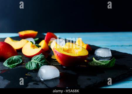 Scheiben reife Nektarinen und Pfirsiche auf schwarzem Stein. Frisches Obst Hintergrund. Nektarinen und Pfirsiche als gesunde eatin Stockfoto