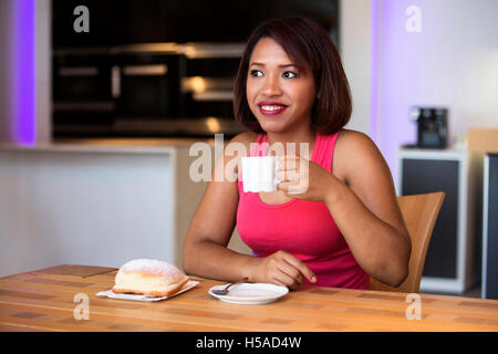schöne spanische Frau sitzt am Tisch mit Kaffee und Gebäck suchen glücklich Stockfoto