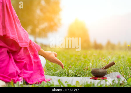 Tibetische Glocke neben Yogaposition auf einer Wiese Stockfoto