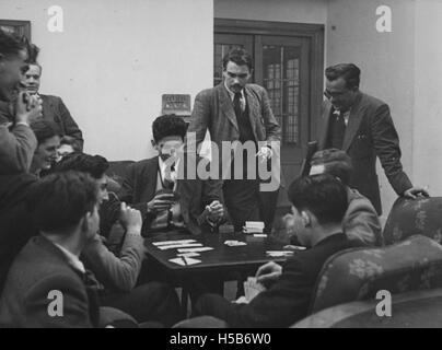 Auf diesem Foto aus dem Jahr 1951 werden Schüler in einem der Gemeinschaftsräume Karten spielen sehen, die soziale Interaktionen in einer akademischen oder privaten Umgebung hervorheben. Diese Szene reflektiert das Studentenleben in den frühen 1950er Jahren, wobei Kartenspiele unter Gleichaltrigen in gemeinsamen Wohnräumen als gemeinsame Freizeitbeschäftigung dienen. Stockfoto