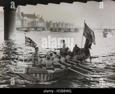 Dieses Foto zeigt Ruderer, die während der Olympischen Spiele 1948 in London die olympische Flagge tragen, was die Eröffnung der Spiele und die Rolle der Athleten bei der Zeremonie symbolisiert. Stockfoto