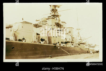 Die HMS Hood, ein britischer Schlachtkreuzer, wird 1926 an einem Kai angedockt. Dieses Foto zeigt die Pracht eines der berühmtesten Schiffe der Royal Navy vor seinem Einsatz im Zweiten Weltkrieg. Die Hood war ein Symbol der Marinekraft und war für ihre Größe und Feuerkraft bekannt. Stockfoto