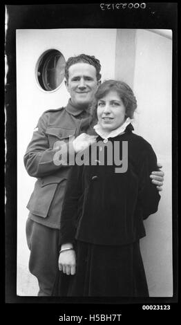 Ein Foto, das zwischen 1910 und 1929 aufgenommen wurde und einen nicht identifizierten Mann und eine Frau zeigt, die in der Nähe eines Bullauchs eines Schiffes stehen. Das Bild zeigt einen Moment an Bord eines Schiffes, wahrscheinlich während der Reise oder als Teil eines maritimen Ereignisses. Stockfoto