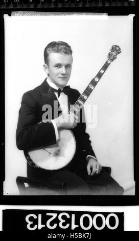 Ein Porträt eines Mannes, der ein Banjo hält, ein ikonisches Streichinstrument, das häufig mit Folk-, Bluegrass- und Country-Musik assoziiert wird. Dieses Bild zeigt wahrscheinlich einen Musiker oder eine Kulturfigur aus einer bestimmten Zeit. Stockfoto