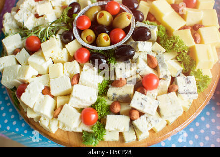 Weißer und gelber Käse, Tomaten und Oliven auf Holzplatte Stockfoto
