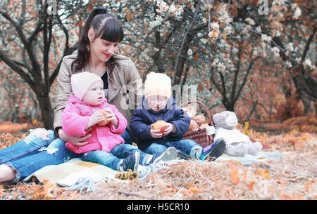 Herbst Park-Mutter mit Zwillingen auf Plaid im Freien im Apfelgarten Stockfoto