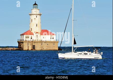 Ein Segelboot vorbei vor der Chicago Hafen Leuchtturm an einem Sommerabend wie es spiegelt dies wider. Chicago, Illinois, USA. Stockfoto