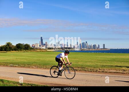 Ein einsamer Radfahrer Radeln entlang eines Pfades im Süden von Chicago Seite mit einem Panoramablick auf die Stadt. Chicago, Illinois, USA. Stockfoto