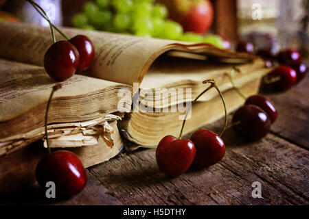 Retro-Buch auf hölzernen Hintergrund und Cherry berry Stockfoto