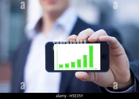 Geschäftsmann zeigt Smartphone-Bildschirm mit nachhaltigen Ergebnissen auf grüne Balkendiagramm Stockfoto