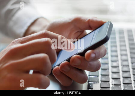 Leader Kontaktaufnahme mit seinem Business Team mit Smartphone und Laptop zur Hand Stockfoto