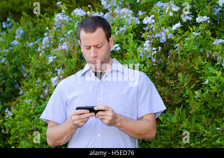 Mann verärgert auf einem Smartphone spielen Pokemon gehen. Stockfoto