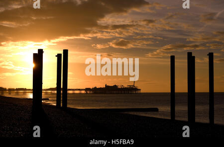 Brighton, Sussex, UK. 21. Oktober 2016. Die Sonne geht über die verfallenen Säulen der alten West-Pier mit dem Palace Pier in der Ferne auf Brighton Beach früh wie der Wetterbericht wieder sonniges Wetter im Süden von der UK-Credit: Simon Dack/Alamy Live News Stockfoto