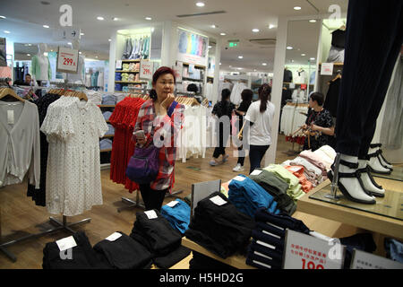 Eine Chinesin ist mit Blick auf Kleidung und betrachten, was Sie kaufen bei einem Uniqlo in Sanlitun. Peking, China. 25.04.2016. Stockfoto