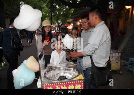 Eine chinesische Hausierer ist eine frisch gemachte weiße Zuckerwatte zu einem Kind übergeben, der mit seinen Eltern und seiner Großmutter wartet. Stockfoto