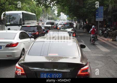 Schwerverkehr, viele moderne Autos und ein Bus, ein Stau und Roller fahren auf eine spezielle Nebenfahrbahn. Peking, China. 26.04.2 Stockfoto