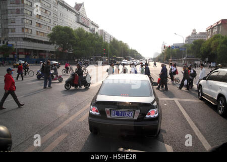 Roller, Fahrräder und Fußgänger überqueren gemeinsam die breite Straße vor Autos warten auf rotes Licht auf Grün ändern. Stockfoto