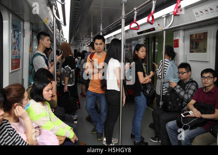 Chinesen fahren die Guangzhou Metro-Bahn oder u-Bahn, viele von ihnen spielen mit Smartphones. Guangzhou, China. 04.05.2016. Stockfoto