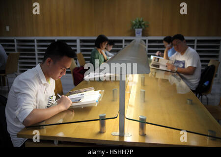 Junge Chinesen Menschen sitzen und lesen in der Bibliothek. Bibliothek von Shenzhen, Shenzhen, China. 05.05.2016. Stockfoto