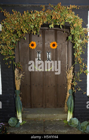 Großbritannien, England, Cheshire, Siddington, All Saints Church, Erntefest, Sonnenblumen und Stangenbohnen lächelndes Gesicht auf West-Tür Stockfoto