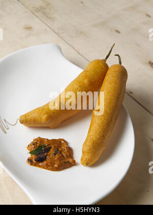 Chili bajji mit Zwiebelchutney ein südindischer Snack auf einer Tauchplatte mit Holzhintergrund Stockfoto