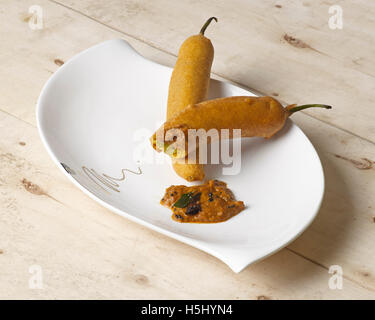 Chili bajji mit Zwiebelchutney ein südindischer Snack auf einer Tauchplatte mit Holzhintergrund Stockfoto