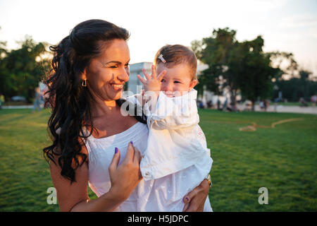 Glückliche Mutter ihre kleine Tochter hielt und Lachen im park Stockfoto