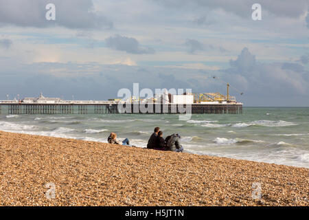 Leute sitzen am Strand von Brighton Pier von Brighton zu betrachten, im Herbst, Brighton, East Sussex England UK Stockfoto