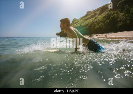 Richtungskontrolle Ansicht der junge Mann tut Wasser im Meer Surfen. Männliche Surfer in das Meerwasser mit Surfbrett. Stockfoto