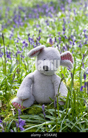 Des Kindes Stofftier Maus sitzen unter den Glockenblumen. Stockfoto