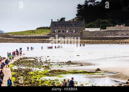 ein Blick auf Menschen, auf dem Damm von eingehenden überwältigt Gezeiten eine St. Michael Bay und Küste in Cornwall. Stockfoto