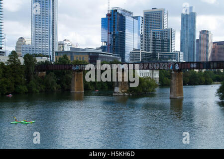 Austin, Texas. Blick von Town Lake die Pfluger Fußgängerbrücke mit Graffiti über die Bahnbrücke und Kajaks im Wasser. Stockfoto