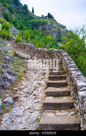 Die Ruinen der alten Festungsmauer mit abgenutzten Steinstufen führt zum Gipfel Berges, Kotor, Montenegro. Stockfoto