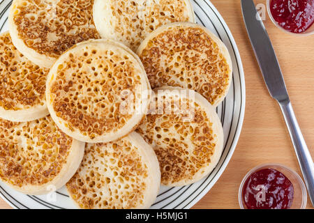 Großer Teller mit frisch geröstetem Fladenbrot und Erdbeer-Marmelade mit einem Messer auf einen Frühstückstisch Stockfoto