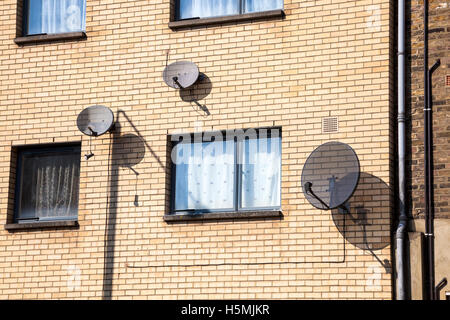 Satellitenschüsseln Aufhängen an der Wand eines Wohnhauses, London, UK Stockfoto