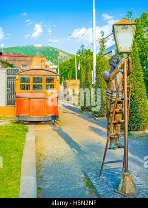 Die Statue des alten Anzünder, Festsetzung der Straßenlaterne und der Oldtimer-Straßenbahn auf dem Hintergrund Stockfoto