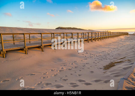 Holzsteg bedeckt im Sand in der Nähe von der Atlantik-Küste in der Nähe von Praia da Crismina Strand bei Sonnenuntergang, Portugal Stockfoto