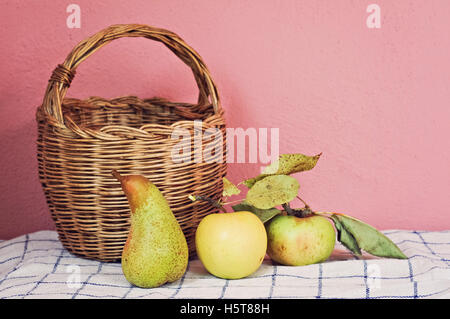 Früchte von Weidenkorb Rosa Wand auf Tisch Stockfoto