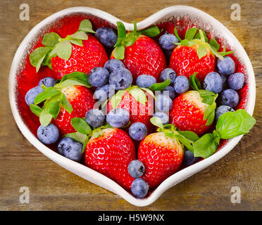 Beeren im Herzen geformte Schale. Gesunde Ernährung-Konzept. Ansicht von oben Stockfoto