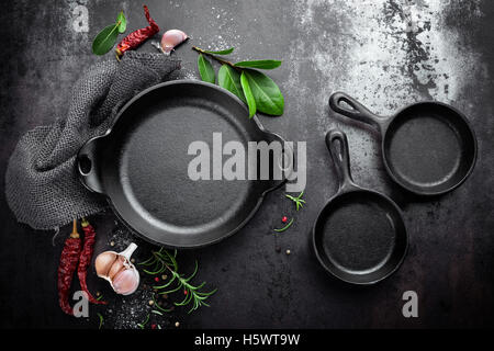 Gusseisen Pfanne und Gewürzen auf schwarzem Metall kulinarischen Hintergrund, Ansicht von oben Stockfoto