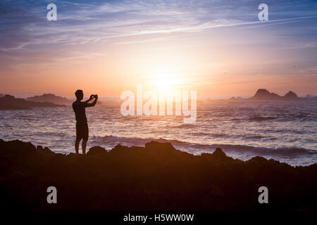 Junge Erwachsene nehmen Foto von erstaunlichen Abendlicht am Strand Stockfoto