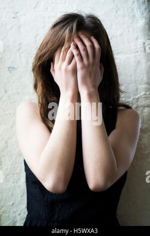 Junge Frau Gesicht mit Händen versteckt Stockfoto