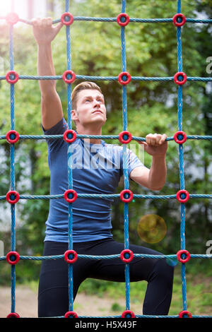 junge hübsche Sportler Klettern auf eine Netto Stockfoto