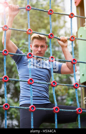 junge hübsche Sportler Klettern auf einem Netz im freien Stockfoto